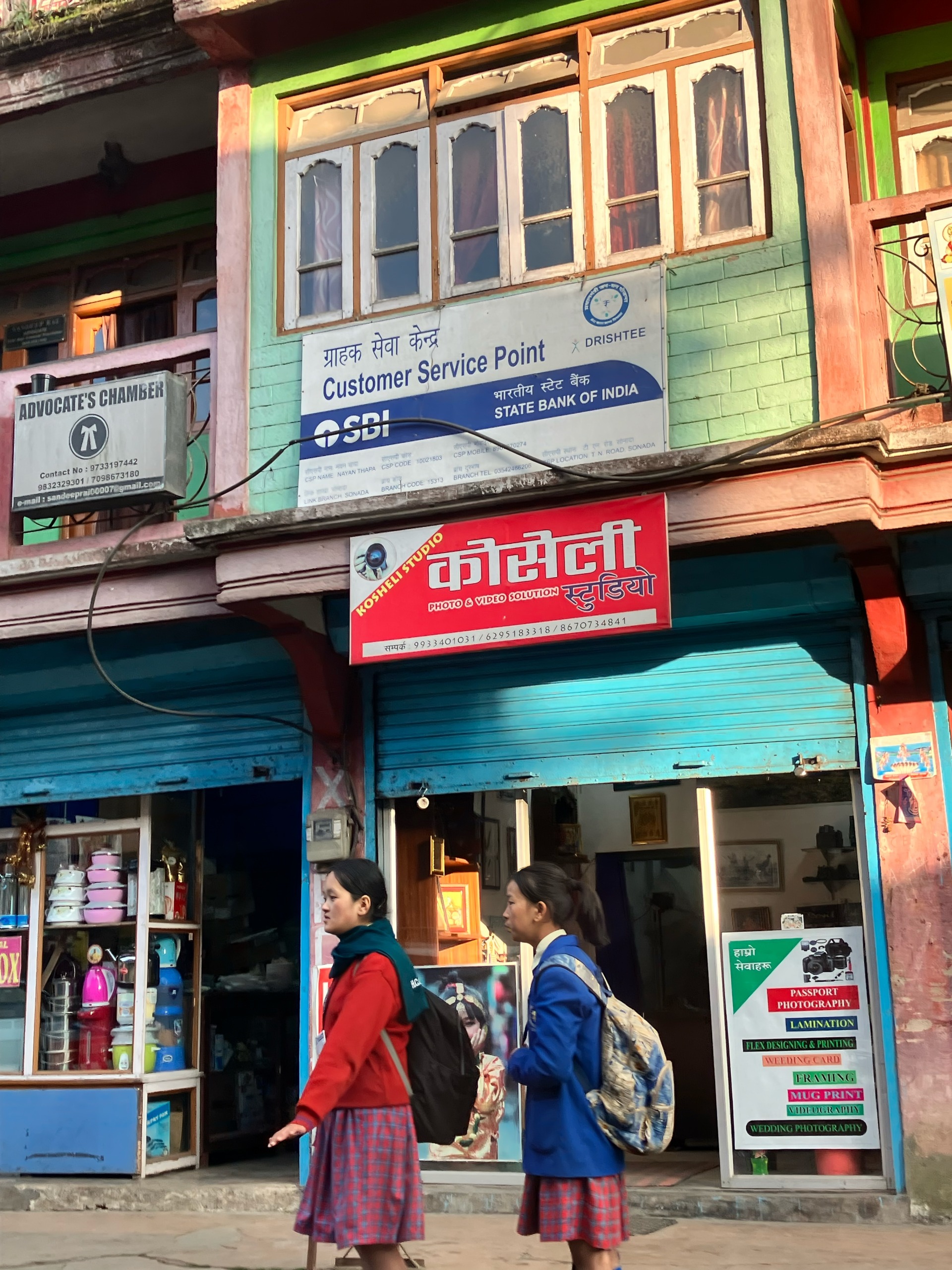 Schoolgirls pass by a local lending point as credit enters ordinary life